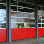 Närbild på rödvita takskjutportar med några fönstersektioner